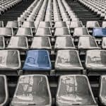 Empty stadium seats with a blue chair in the middle.