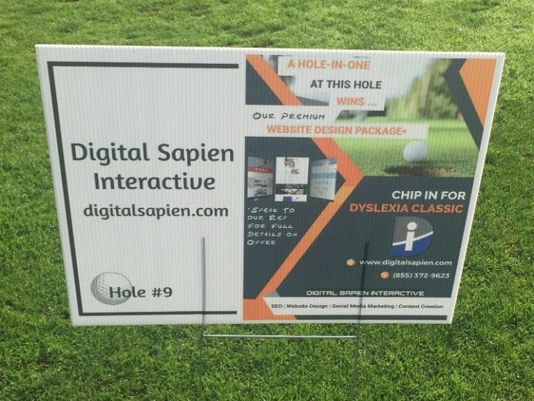 A sign for digital saphire interactive on a grassy field.