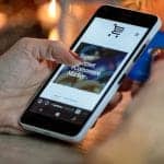 A woman is holding a credit card on a smartphone.