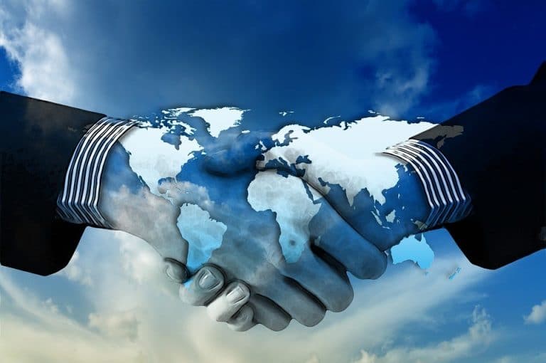 Two business people shaking hands over a world map.